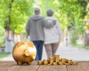 gold piggy bank with coins in front of a couple walking away in the background