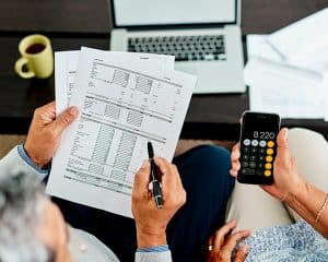 2 people looking at Medicaid forms holding a pen and a calculator at a desk