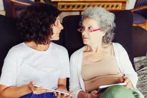 Aging strategies. Daughter explaining internet app specifics to senior mother. Middle aged woman and elderly mother, holding tablets and talking.