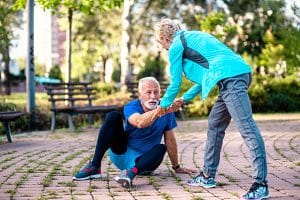 Reduce Fall Risk. Senior woman helping her husband to stand up after fall while they were jogging.