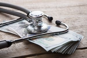 cost of healthcare symbolized by stack of cash and a stethescope