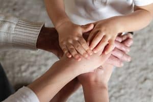 Grandfather, his daughter and little grandson together make a stack of palms and hands. Happy family togetherness. Happy family and support for elderly parents concept.