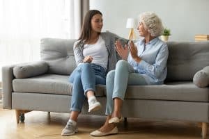 Young woman talking with elderly mom indoors about estate planning.