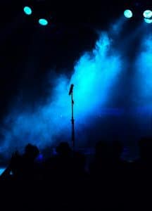 empty blue stage microphone in the center silhouette of audience. Representing questions about Meat Loaf's estate plan