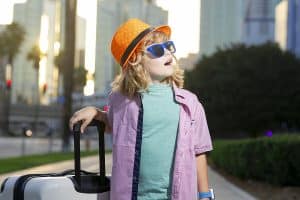 Child with travel suitcase on vacation. Kids travel and adventure concept. Child boy going on vacation holding luggage travel bag outdoor.