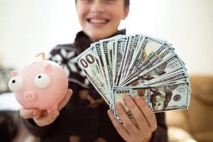 A happy minor child with a wad of money in his hands. Eaten money collected in the piggy bank. Cashing coins from the piggy bank.Beneficiary of IRA.