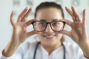 Female ophthalmologist doctor holding glasses in ophthalmology clinic. donating medical equipment.