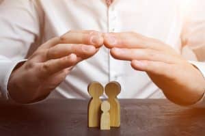 Hands covering wooden family figurines