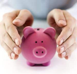 Hands covering piggy bank to protect