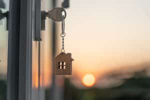 Key in door lock, setting sun behind a house shaped keychain