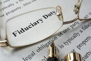 The definition of fiduciary duty typed on paper and a pair of glasses on top to magnify the words FIDUCIARY DUTY