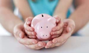 Piggy bank in child's hands, inside parent's hands - protecting investments