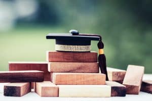 Black graduation cap and tassle on top of wooden building blocks