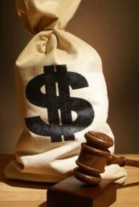 A brown sack full of money with a large dollar sign printed on it. A gavel is resting in front of the sack of money. Legal expenses