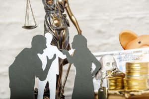 Silhouettes of people in conflict, silhouette of judge behind them, justice scale and money in background