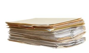 a pile of file folders on a white background shows paperwork leads to probate delays