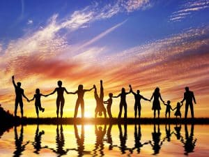family and friends at a Celebration of Life holding hands at sunset near the water