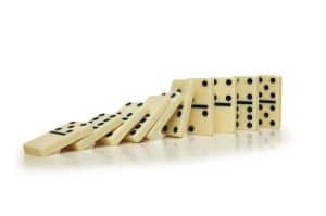 a row of dominoes stacked upright and falling over - the domino effect