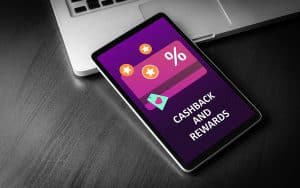 cell phone lying screen side up next to a laptop - screen displays reward benefits