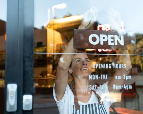 small business owner hanging OPEN sign in window