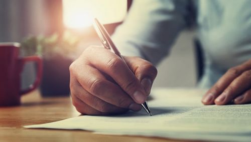 Close up of a person writing a letter by hand with a pen