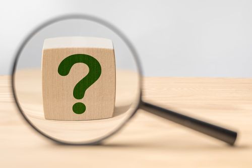 Magnifying glass with question mark in focus on wooden cube. Search for an answer to question. Research, searching or investigating something. estate planning questions