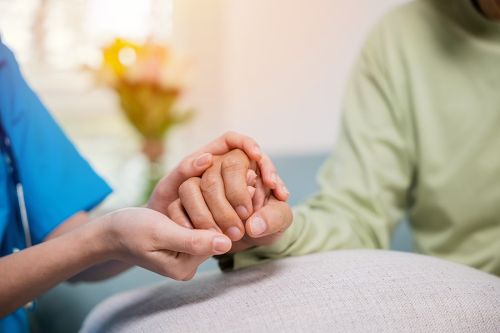 Caretaker holding hands of older patient