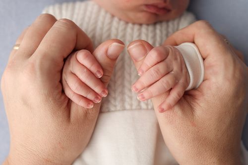 new born baby gripping parent's thumbs tightly