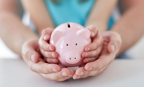 Piggy bank in child's hands, inside parent's hands - protecting investments