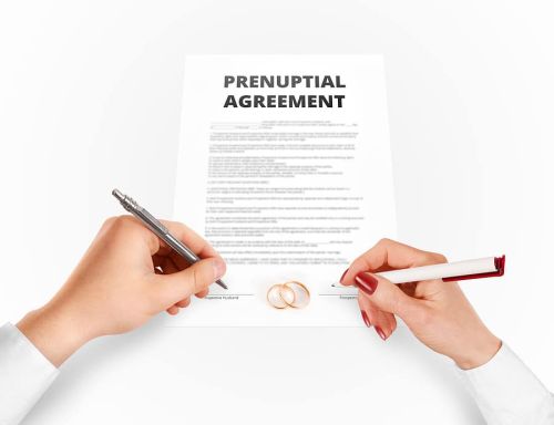 Disinheriting a Spouse related to a prenuptial agreement. Man and woman sign prenuptial agreement near gold rings. Legal prenup document contract signing by newlywed couple. Marry partners signature on prenupt statement. Wedding ceremony conflict text.