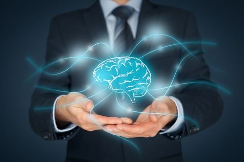 man in suit with hands out open in front of him holding a holographic image of a brain