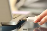 Close up of woman hands connecting usb flash drive on a laptop computer to organize financial information.