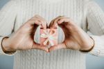 Image of person holding a wrapped gift while hands are shaped in a heart