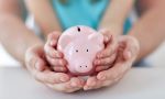 Piggy bank in child's hands, inside parent's hands - protecting investments