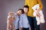 Two minor children boys hugging their mother at home