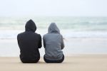 two males sitting on beach